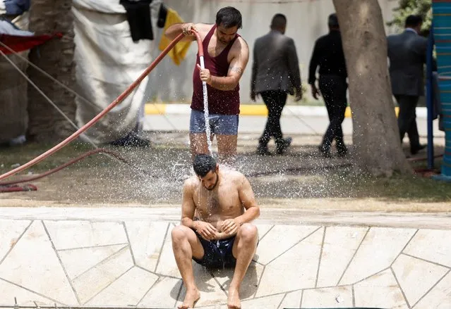 Supporters of Iraqi populist leader Moqtada al-Sadr cool off during high temperatures as they take part in a sit-in at the parliament building, amid the political crisis, in Baghdad, Iraq on August 7, 2022. (Photo by Khalid Al-Mousily/Reuters)