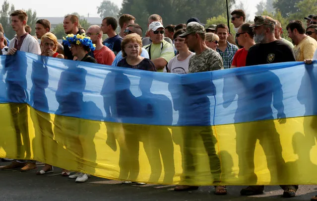 Pro-Ukrainian activists hold a national flag as they protest against a procession petitioning for peace organized by the Ukrainian Orthodox Church of the Moscow Patriarchate, in the city of Boryspil outside Kiev, Ukraine, July 25, 2016. (Photo by Valentyn Ogirenko/Reuters)