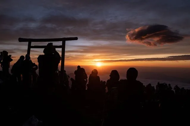 People watch the sunrise from the summit of Mount Fuji early on August 15, 2022, some 70 kilometres (43 miles) west of the capital Tokyo. (Photo by Philip Fong/AFP Photo)