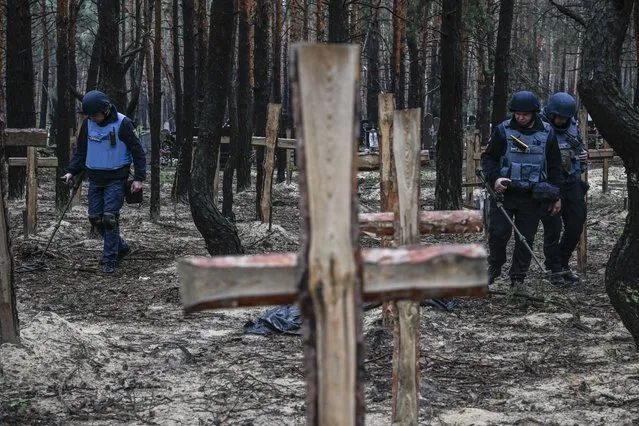 Ukrainian servicemen search for land mines at a burial site in a forest on the outskirts of Izyum, eastern Ukraine on September 16, 2022. Ukraine said on September 16, 2022 it had counted 450 graves at just one burial site near Izyum after recapturing the eastern city from the Russians. (Photo by Juan Barreto/AFP Photo)