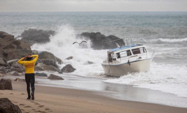 A Lifeguard observes a boat that was sent into the rocks on Deer Creek beach after heavy winds during a storm on December 21, 2023 in Oxnard, California. Southern California saw heavy rain storms that caused flooding and led to evacuations in Ventura County. (Photo by Apu Gomes/Getty Images)