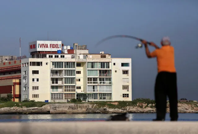 A banner is seen on the roof of a building as a fisherman holds a rod at Havana's seafront boulevard “El Malecon”, Cuba, August 5, 2016. The banner reads “Long live Fidel”. (Photo by Enrique de la Osa/Reuters)