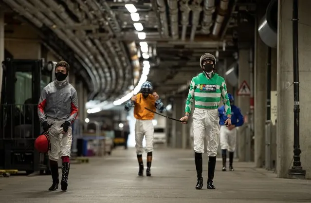 Jockeys walk through the service tunnel from the auxiliary weighing room towards the paddock, as racing resumes behind closed doors after the outbreak of the coronavirus, on June 16, 2020 in Ascot, England. (Photo by Edward Whitaker/Pool via Reuters)