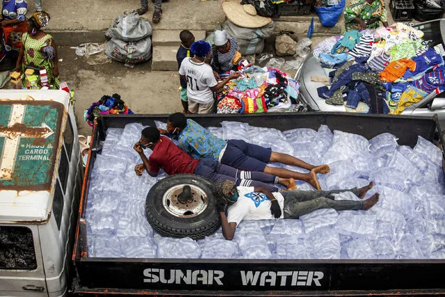 Men sleep on top of packets of sachet water arranged in a truck driven through a market in Mafoluku district, Lagos, Nigeria, 20 May 2020. With Lagos as the epicentre of the coronavirus disease in Nigeria, the most populous country in Africa has a record of 6,401 confirmed cases of the coronavirus, according the data shown on the Nigeria Centre for Disease Control website on 20 May 2020. (Photo by Akintunde Akinleye/EPA/EFE/Rex Features/Shutterstock)