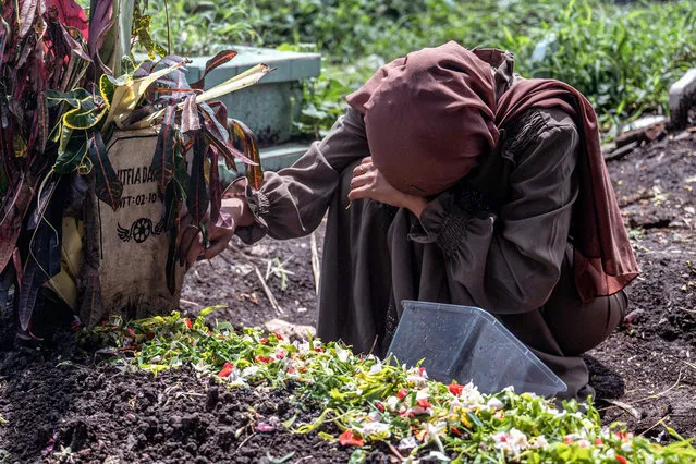 Ismiatul Urmila, the sister of Lutvia Damayanti, one of 131 people killed in the October 1 Kanjuruhan football stadium disaster, mourns over her grave in Malang, East Java on October 7, 2022. (Photo by Juni Kriswanto/AFP Photo)