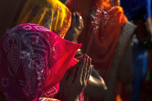 Hindu devotees gather by the river Brahmaputra and offer prayers during Chhath Puja festival in Guwahati, northeastern Assam state, India, Sunday, October 30, 2022. During Chhath, an ancient Hindu festival, rituals are performed to thank the Sun god for sustaining life on earth. (Photo by Anupam Nath/AP Photo)