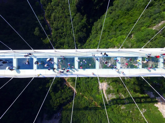 Visitors walk across a glass-floor suspension bridge in Zhangjiajie in southern China's Hunan Province Saturday, Aug. 20, 2016. The bridge, which opened to the public on a trial basis on Saturday, spans 430 meters (1,410 feet) and rises about 300 meters (984 feet) above a valley in a scenic zone, making it the world's highest and longest glass-bottomed bridge according to Chinese state media. (Chinatopix via AP)