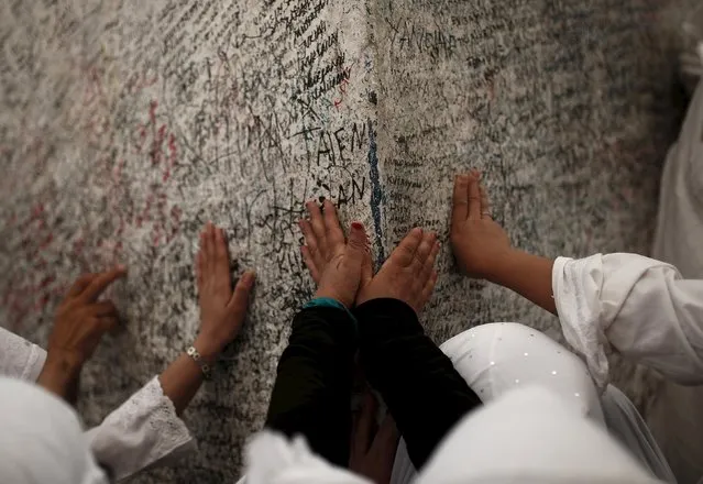 Muslim pilgrims touch a rock atop Mount Mercy on the plains of Arafat during the annual haj pilgrimage, outside the holy city of Mecca September 22, 2015. (Photo by Ahmad Masood/Reuters)