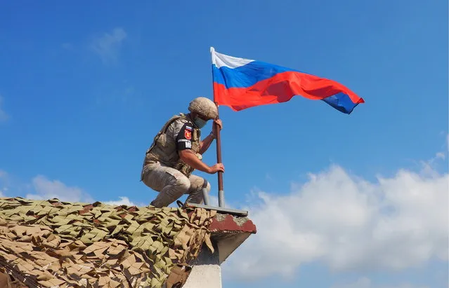 A Russian military police officer with a Russian national flag is seen during a joint patrol of the M4 Motorway with Turkish troops in the Idlib de-escalation zone in northeast Syria in Latakia Province, Syria on July 22, 2020. For the first time, Russia and Turkey jointly patrolled the whole M4 motorway to provide a safe link between Aleppo and Latakia. In March 2020, the presidents of Russia and Turkey met for talks in Moscow and reached an agreement about a ceasefire and joint patrols to alleviate the situation in north-eastern Syria. (Photo by Andrei Gryaznov/TASS via Getty Images)