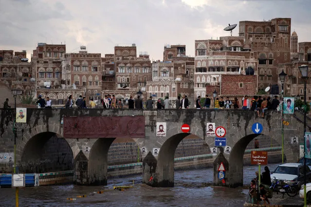 People stand on a bridge to watch flood water in the Old City of Sanaa, Yemen August 2, 2016. (Photo by Khaled Abdullah/Reuters)