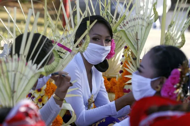 Women wearing face masks wait to join a parade in Bali, Indonesia, on Thursday, July 30, 2020. Indonesia's resort island of Bali will reopen for domestic tourists on Friday after months of virus lockdown. (Photo by Firdia Lisnawati/AP Photo)