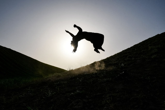 An Afghan man performing parkour is silhouetted against the setting sun during a practice session at a hilltop in the Sarmang village of Sholgara district, Balkh province on April 14, 2025. (Photo by Atif Aryan/AFP Photo)