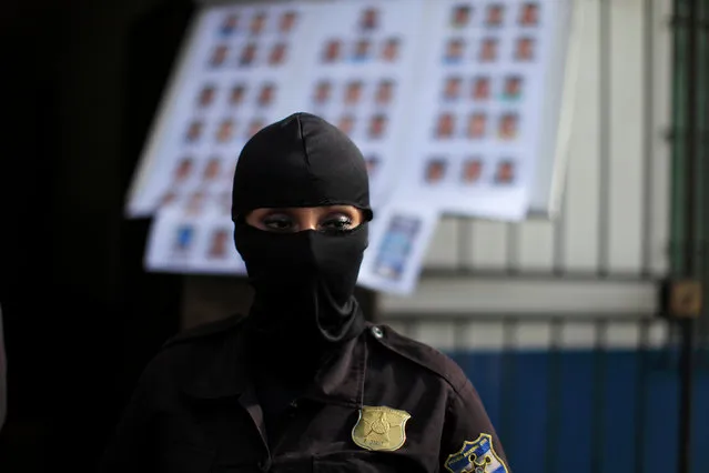 Policewoman observes suspected gang members as they are presented to the media after being detained by the police under the charges of homicide and terrorism in San Salvador, El Salvador on September 8, 2016. (Photo by Jose Cabezas/Reuters)