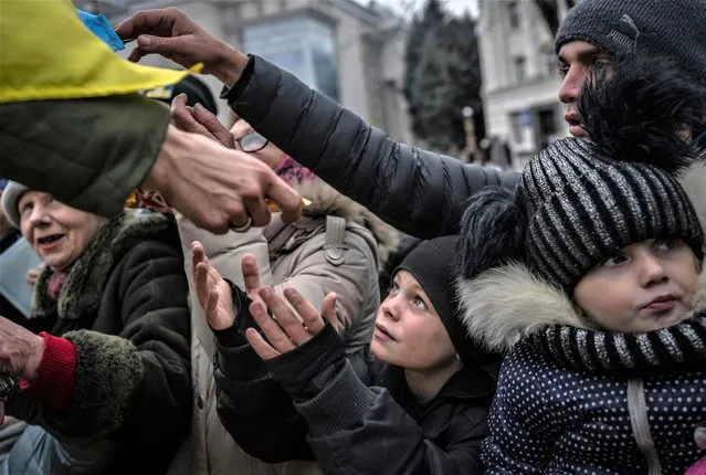 A child receives aid supplies in the centre of Kherson on November 18, 2022, amid the Russian invasion of Ukraine. (Photo by Bulent Kilic/AFP Photo)
