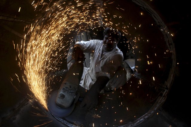 A technician uses an electric grinder to shape an oven to be used for baking bread at a workshop in Lahore, Pakistan, September 3, 2015. (Photo by Mohsin Raza/Reuters)