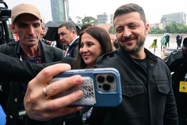 Ukraine's President Volodymyr Zelensky takes a selfie with supporters as he arrives for the family photo at at the European Political Community (EPC) summit, in Tirana on May 16, 2025. (Photo by Leon Neal/Pool via AFP Photo)
