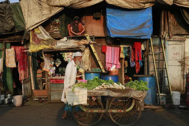 A vegetable seller pushes his cart at a slum area in Mumbai, India's financial capital and largest city, Tuesday, November 11, 2014. A whopping 41 percent of households in Mumbai were located in overcrowded shantytowns, where most residents are squatting illegally and many have little access to basic sanitation, according to a 2013 census report with India's first complete count of its vast slum population. (Photo by Rafiq Maqbool/AP Photo)