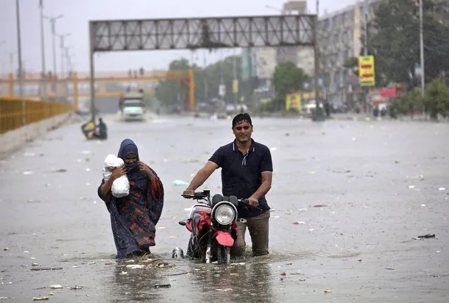 A family wades through a flooded road during a heavy monsoon rainfall in Karachi, Pakistan, Tuesday, August 25, 2020. Three days of monsoon rains have killed dozens of people and damaged hundreds of homes across Pakistan, the country's national disaster management agency said Tuesday, as another spell of heavy rain lashed the port city of Karachi. (Photo by Fareed Khan/AP Photo)