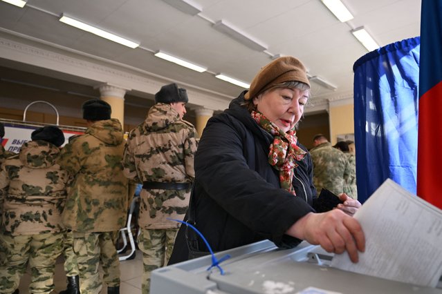 A woman casts her ballot as service members register to vote during Russia's presidential election in Moscow on March 15, 2024. (Photo by Natalia Kolesnikova/AFP Photo)