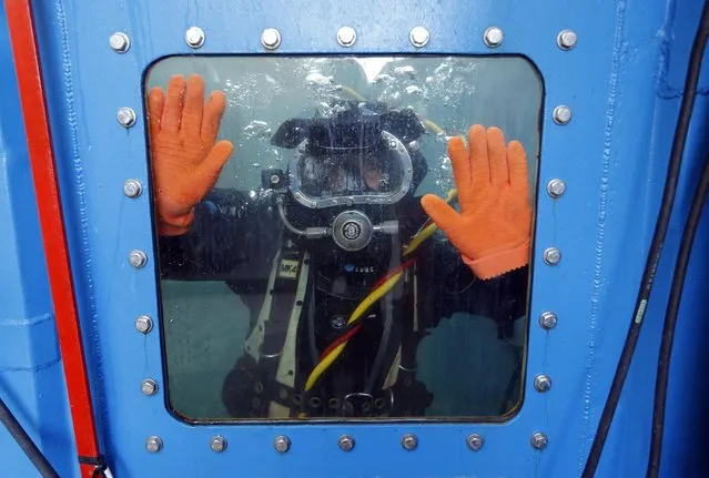 A commercial diver prepares to work in a pool during a training session at the National Diving School in Saint-Mandrier near Toulon, South Eastern France, November 19, 2014. The school, member of the IDSA (International Diving School Association), trains professional commercial divers for jobs in marine engineering, on oil platforms in the petroleum industry, and for water pipelines conduits used in the nuclear industry. (Photo by Jean-Paul Pelissier/Reuters)