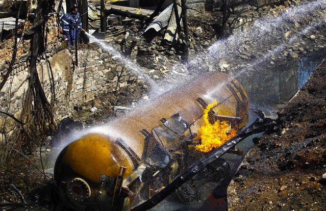 Firefighters try to extinguish a fire on a gas tanker on the outskirts of Mumbai, India, on March 4, 2013. One person died and 14 were injured when the tanker caught fire. (Photo by Rafiq Maqbool/Associated Press)
