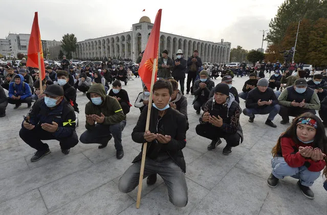 People pray during a rally on the central square in Bishkek, Kyrgyzstan, Friday, October 9, 2020 Sooronbai Jeenbekov, the embattled president of Kyrgyzstan, has moved to end the political turmoil that followed a disputed parliamentary election, ordering a state of emergency in the capital. Jeenbekov has faced calls to resign by protesters who stormed government buildings after Sunday’s parliamentary vote was reportedly swept by pro-government parties. Protesters freed former President Almazbek Atambayev, who was jailed on charges seen by his supporters as a political vendetta. (Photo by Vladimir Voronin/AP Photo)