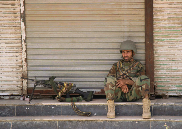 An Afghan National Army (ANA) soldier sits in front of a closed shop in the downtown of Kunduz city, Afghanistan October 3, 2016. (Photo by Nasir Wakif/Reuters)