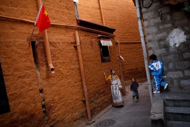 A woman in traditional clothes poses during a photoshoot as a boy watches in an alley in the old city of Lhasa, during a government organised tour of the Tibet Autonomous Region, China, October 14, 2020. (Photo by Thomas Peter/Reuters)