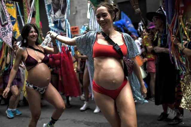 Pregnant revelers dance during a street pre-carnival party by the “Cordao do Boitata” Block, in Rio de Janeiro, Brazil, Sunday, February 12, 2023. Revelers are taking to the streets for the open-air block parties, leading up to Carnival's official Feb. 17th opening. (Photo by Bruna Prado/AP Photo)
