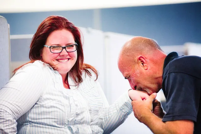 Happily embarrassed female cubicle worker reacts to kiss given on her hand by a male colleague. She gushes at the camera in a cute manner. (Photo by Nicolas McComber/Getty Images/iStockphoto)