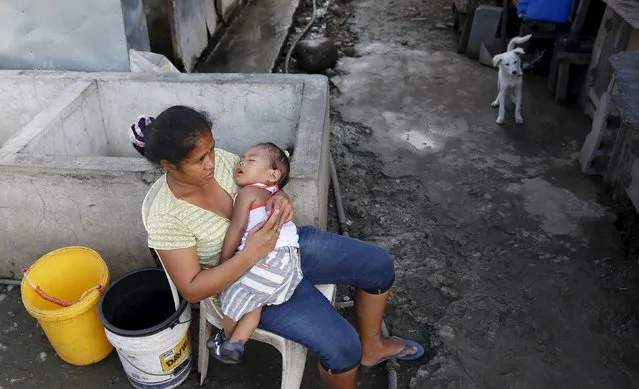 A woman holds her child while waiting for a water ration at a transitional shelter for Typhoon Haiyan survivors in Tacloban city November 1, 2015, ahead of the second anniversary of the devastating typhoon that killed more than 6000 people in central Philippines. (Photo by Erik De Castro/Reuters)