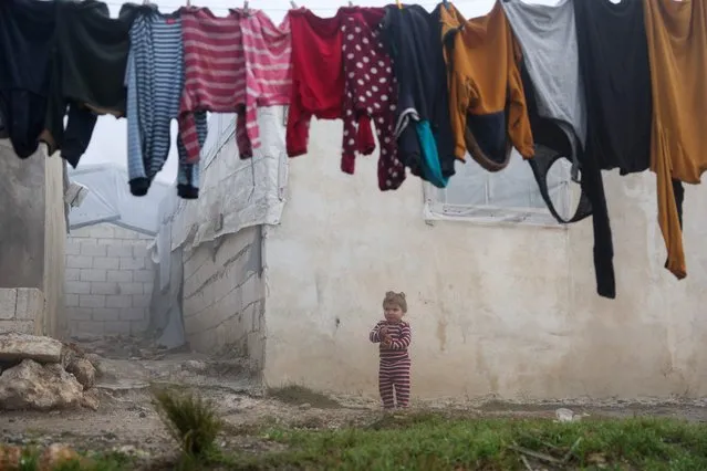 A child plays outdoors on a foggy day at a camp for the internally displaced in the al-Zawf area in the northwestern countryside of Syria's Idlib governorate, near the border with Turkey, on December 17, 2022. (Photo by Omar Haj Kadour/AFP Photo)