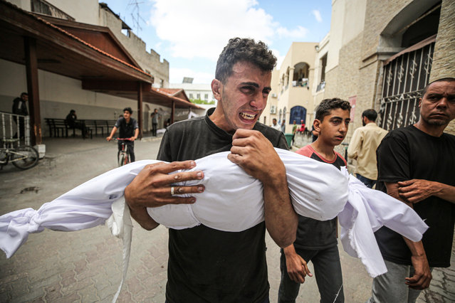 A Palestinian holds his relative killed in the Israeli attacks as Israeli attacks continue in Gaza City, Gaza on May 16, 2024. Bodies brought to al-Ahli Baptist Hospital before burial. (Photo by Dawoud Abo Alkas/Anadolu via Getty Images)