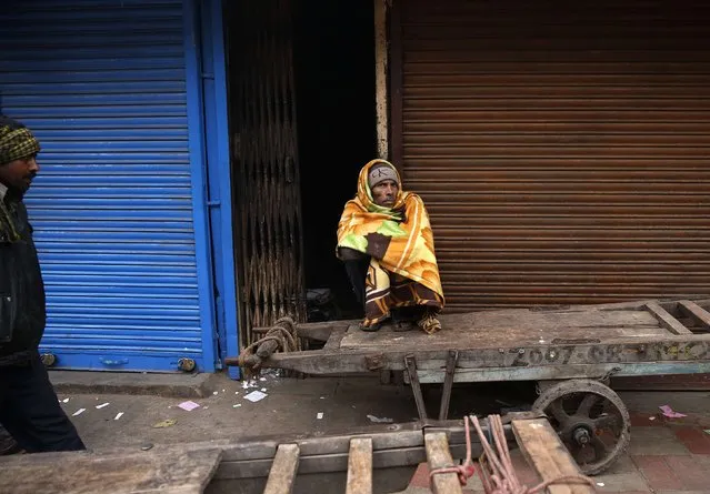 A man wrapped in a blanket sits on a handcart along the roadside on a winter morning in the old quarters of Delhi December 19, 2014. (Photo by Ahmad Masood/Reuters)