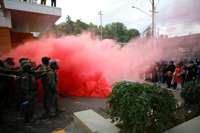 Demonstrators react to a smoke grenade released by law enforcement officers in front of the ICE headquarters in Portland, Oregon, U.S., October 4, 2025. (Photo by Carlos Barria/Reuters)