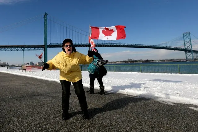 A person holding Canadian flags shouts “Freedom” near Ambassador Bridge, linking Detroit and Windsor, as truckers and their supporters continue to protest against the coronavirus disease (COVID-19) vaccine mandates, in Windsor, Ontario, Canada on February 9, 2022. (Photo by Carlos Osorio/Reuters)