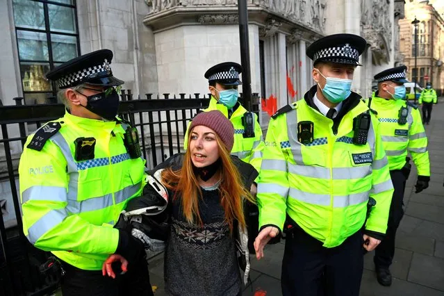 An environmental activist campaigning against a third runway at Heathrow Airport is detained by police officers after throwing paint against the walls of the Supreme Court in London on December 16, 2020 after the verdict on a legal challenge to the proposed runway. London Heathrow airport won Wednesday a Supreme Court challenge over a ruling made earlier this year to block a third runway at Europe's busiest hub on environmental grounds Britain's highest court has overturned February's Court of Appeal ruling that the UK government had failed to take into account climate change commitments when it gave the green light for the third runway in 2018. (Photo by Daniel Leal-Olivas/AFP Photo)