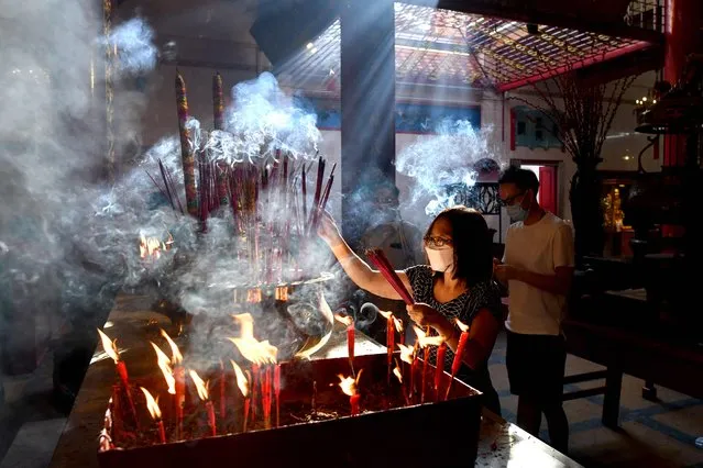 A woman burns incense sticks inside a Chinese temple on the first day of the Lunar New Year in Yangon's Chinatown on January 22, 2023 which ushers in the Year of the Rabbit. (Photo by Sai Aung Main/AFP Photo)