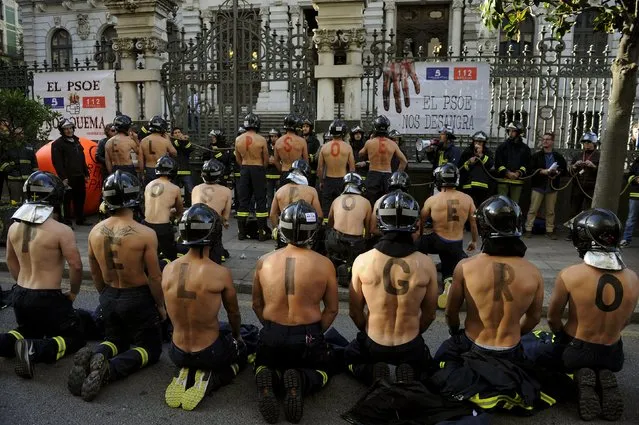 Firefighters take part in a protest in front of the regional parliament of Asturias demanding better salaries and greater standards of public safety in Oviedo, northern Spain, November 19, 2015. The letters painted on the men's backs form the words that read, "The PSOE (Socialist Party of Spain) puts you in danger". (Photo by Eloy Alonso/Reuters)