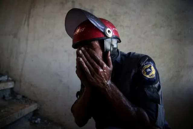 A Civil Defence member rubs his eyes as he tries to put out a fire inside a building after shelling in the rebel held besieged town of Douma, eastern Ghouta in Damascus, Syria October 19, 2016. (Photo by Bassam Khabieh/Reuters)