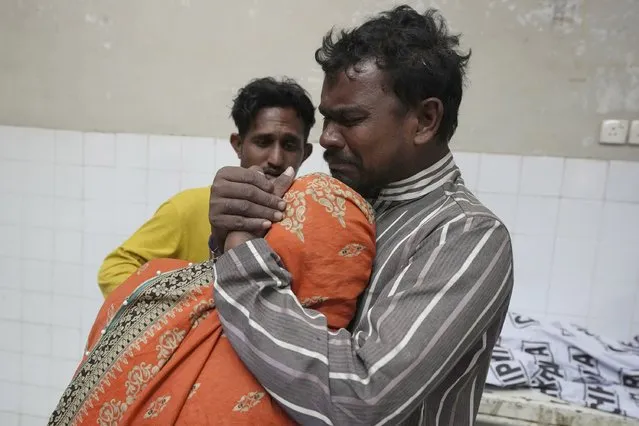 A family mourns next to the body of their family member, who was died in the stampede, at a morgue, in Karachi, Pakistan, Friday, March 31, 2023. (Photo by Fareed Khan/AP Photo)