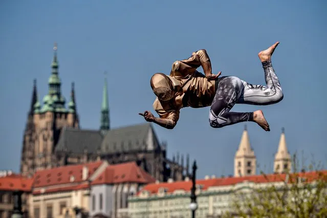 A member of the contemporary circus company Cirk La Putyka perform on the mobile trampoline as he amuses local residents in Prague, Czech Republic, 09 April 2020. The aim of the Cirk La Putyka events in the streets of Czech capital is to get live art back to people during the lockdown. According to them, when people can't go to the artists, to the theater, the actors go to the people. The Czech government has imposed a lockdown in an attempt to slow down the spread of the pandemic COVID-19 disease caused by the SARS-CoV-2 coronavirus. (Photo by Martin Divisek/EPA/EFE)