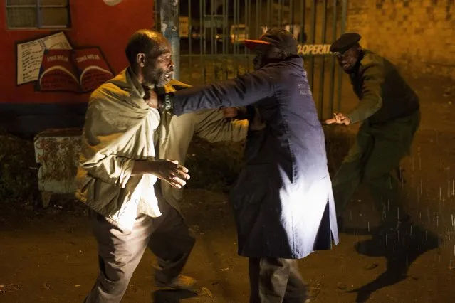 A police officer intervenes to stop two men fighting on a street in Korogocho during a night patrol in Nairobi, Kenya, October 30, 2015. (Photo by Siegfried Modola/Reuters)