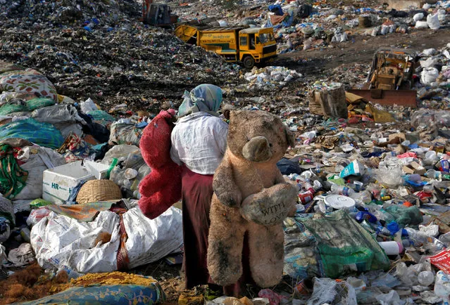 A woman carries stuffed toys through a dump site on the outskirts of Mumbai, India, June 4, 2018. (Photo by Francis Mascarenhas/Reuters)