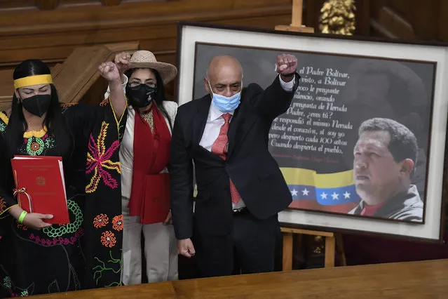 Jorge Rodriguez, right, lifts his fist after being sworn-in as president of the National Assembly, in front of a photo of late President Hugo Chavez, at Congress in Caracas, Venezuela, Tuesday, January 5, 2021. The ruling socialist party assumed the leadership of Venezuela's congress, the last institution in the country it didn't already control. (Photo by Matias Delacroix/AP Photo)