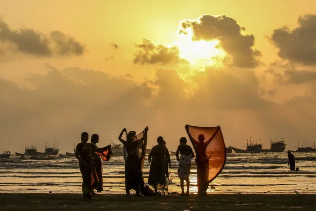 Women hold up their wet clothes to dry after cooling off in the sea water at the Gorai Beach along the Arabian Sea coast in Mumbai, India, 15 May 2023. The Indian Meteorological Department (IMD) issued a heatwave warning for Mumbai and several parts of the state of Maharashtra. (Photo by Divyakant Solanki/EPA)