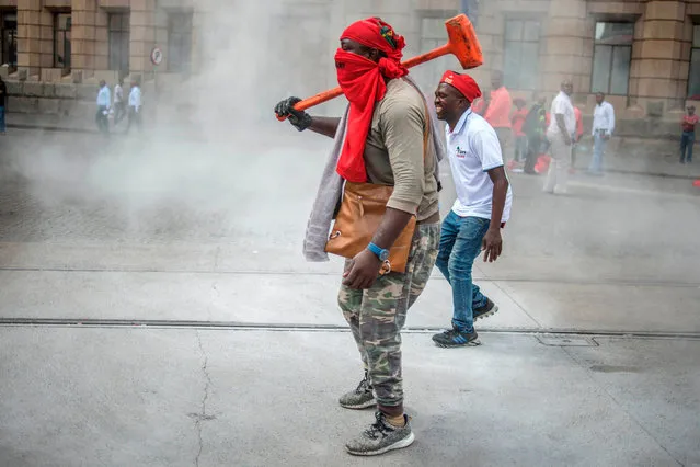 A man carries a sledgehammer as South African opposition Economic Freedom Fighters (EFF) party members and supporters demonstrate against South Africa' s president Jacob Zuma and in support of the release of the South African Public Protector “State Capture” report in Pretoria on November 2, 2016. South Africa' s anti- corruption watchdog November 2 called for prosecutors to investigate alleged criminal activity as it released a report into President Jacob Zuma that fuelled further calls for him to resign. (Photo by Mujahid Safodien/AFP Photo)