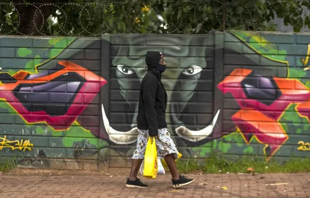 A woman wearing a face mask as a precaution against coronavirus outbreak, walks on the street in downtown Johannesburg, South Africa, Tuesday, January 26, 2021. (Photo by Themba Hadebe/AP Photo)