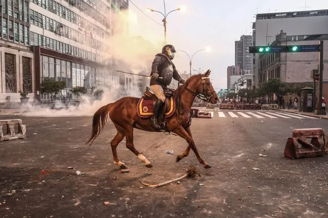 Policemen on horseback ride towards anti-government protestors, in Lima, Peru, 05 April 2022. Thousands of Peruvians defied the curfew ordered by President Pedro Castillo for Lima and its neighboring province of Callao and demonstrated in the capital to demand the president's resignation. (Photo by Aldair Mejia/EPA/EFE)
