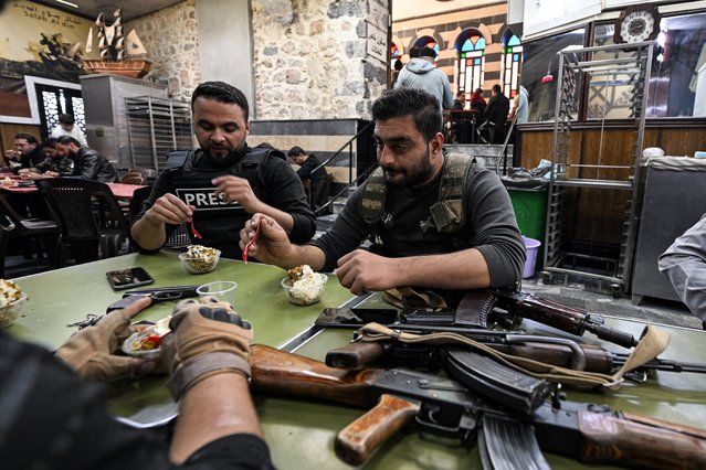Syrian opposition fighters sit for ice cream at the 19th-century Bakdash ice-cream parlour in the Hamidiyah market in the old part of Damascus on December 10, 2024. Islamist-led rebels took Damascus in a lightning offensive on December 8, ousting president Bashar al-Assad and ending five decades of Baath rule in Syria. (Photo by Louai Beshara/AFP Photo)